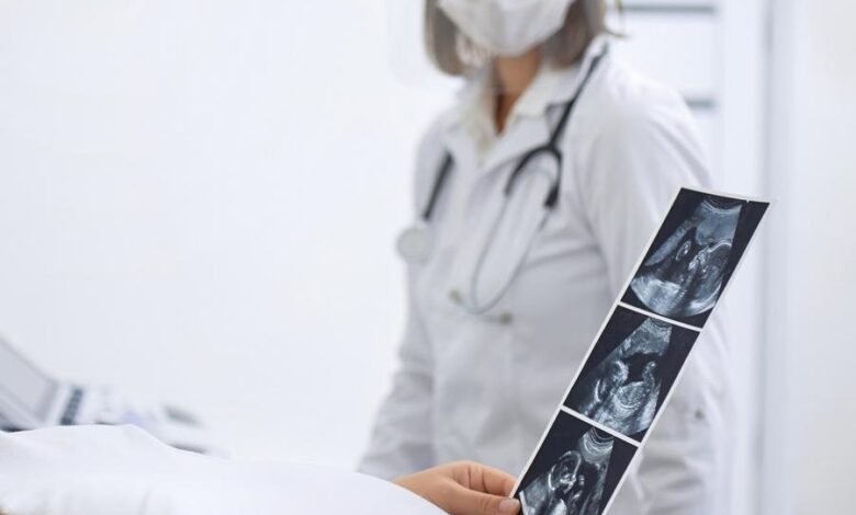 Close Up Of Pregnant Woman Looking At Ultrasound Photos